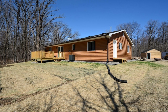 14113 260th St, Dailey Twp, MN 56353 - back of property with log veneer siding, a deck, and central AC