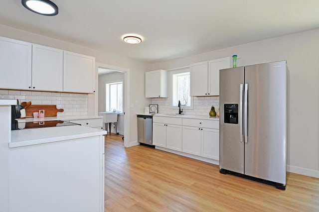 14113 260th St, Dailey Twp, MN 56353 - kitchen featuring stainless steel appliances, a sink, decorative backsplash, light wood finished floors, and light countertops