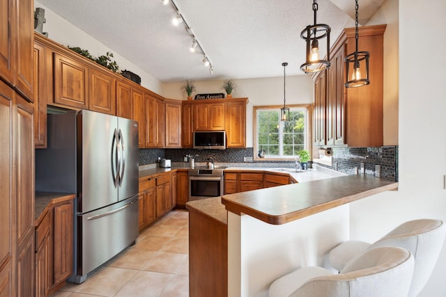 4562 Hummingbird Trl NE, Prior Lake, MN 55372 - kitchen with stainless steel appliances, brown cabinets, a peninsula, backsplash, and a textured ceiling
