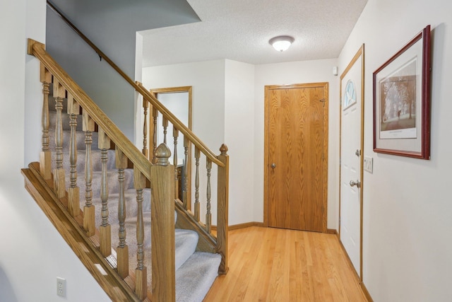8671 Pheasant Run Rd, Woodbury, MN 55125 - foyer entrance with light wood finished floors, stairs, a textured ceiling, and baseboards