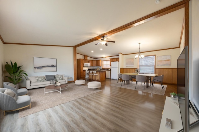 living room with light wood-style flooring, crown molding, wainscoting, ceiling fan with notable chandelier, and vaulted ceiling with beams