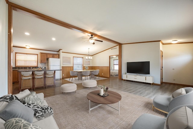 living room with wood finished floors, visible vents, vaulted ceiling, and a wainscoted wall
