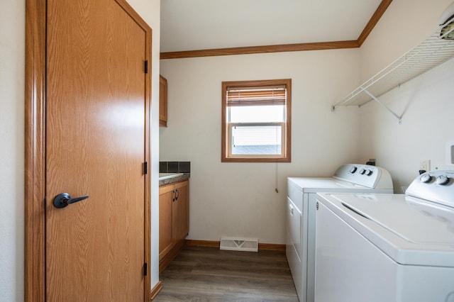 laundry room with visible vents, wood finished floors, washing machine and clothes dryer, baseboards, and cabinet space