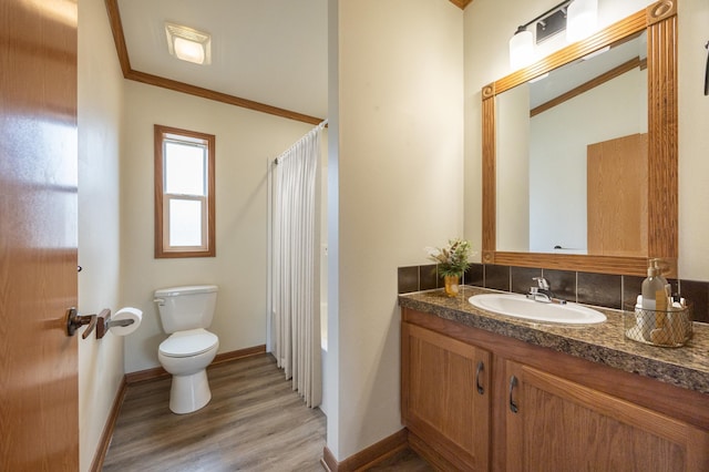 bathroom featuring crown molding, vanity, toilet, wood finished floors, and baseboards