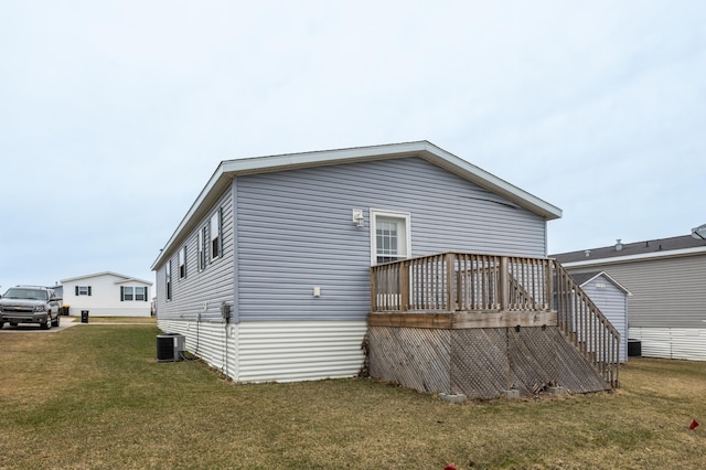 rear view of house with cooling unit, a yard, a wooden deck, and stairway