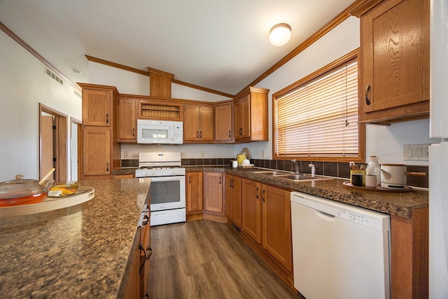 kitchen featuring vaulted ceiling, white appliances, dark countertops, visible vents, and a sink