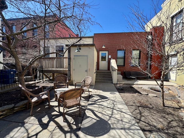 back of property with entry steps, stucco siding, a patio, an outdoor living space, and brick siding