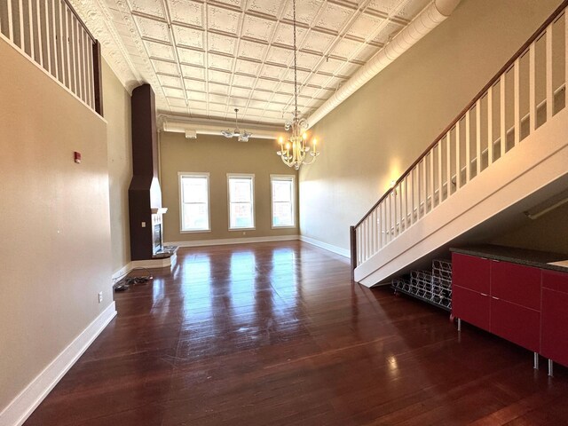 unfurnished living room with baseboards, an ornate ceiling, a chandelier, and hardwood / wood-style floors
