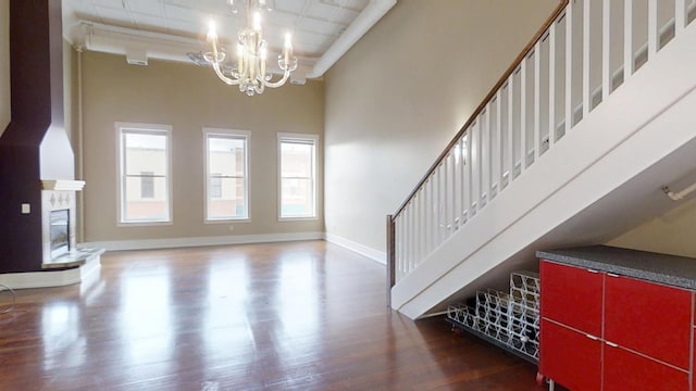interior space with a towering ceiling, baseboards, a chandelier, wood finished floors, and stairs