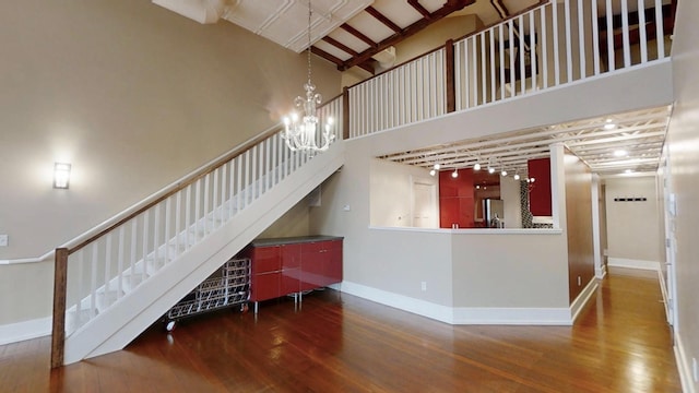 interior space with wood finished floors, a high ceiling, baseboards, and an inviting chandelier