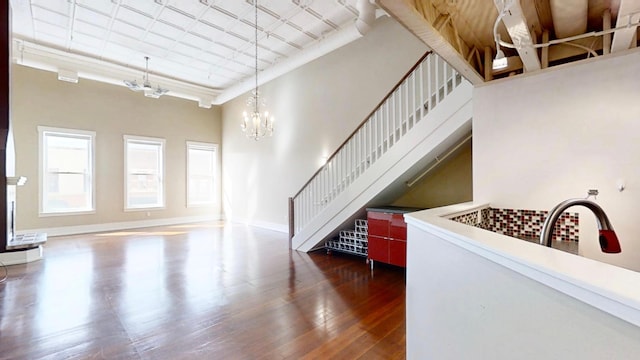 living room with baseboards, wood finished floors, stairs, and a notable chandelier