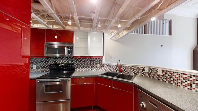 kitchen with dark countertops, red cabinetry, stainless steel appliances, and a sink