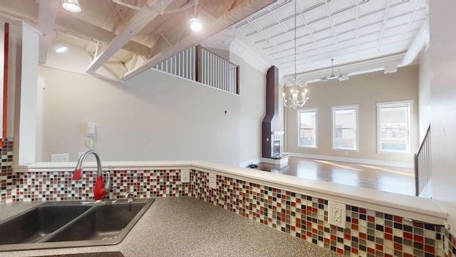kitchen featuring a towering ceiling, tasteful backsplash, a chandelier, and a sink