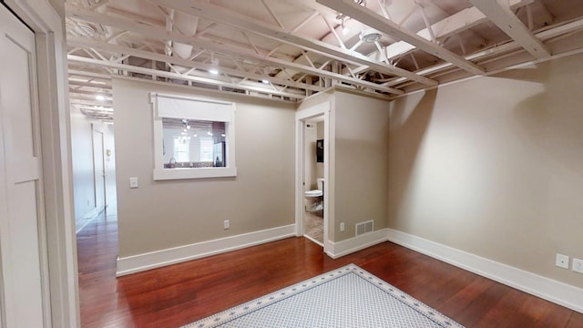 unfurnished room with baseboards, wood finished floors, and visible vents