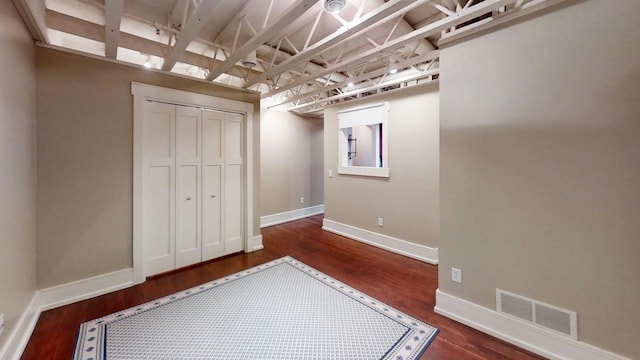 unfurnished bedroom with baseboards, wood finished floors, visible vents, and a closet