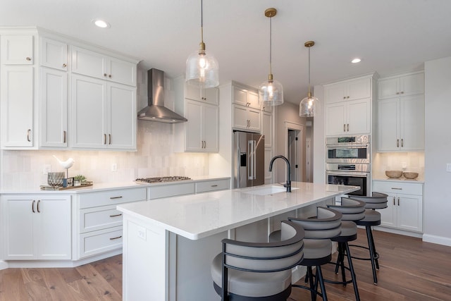 1005 Applewood Ct, Mankato, MN 56001 - kitchen featuring light countertops, a breakfast bar, wall chimney exhaust hood, stainless steel appliances, and a sink