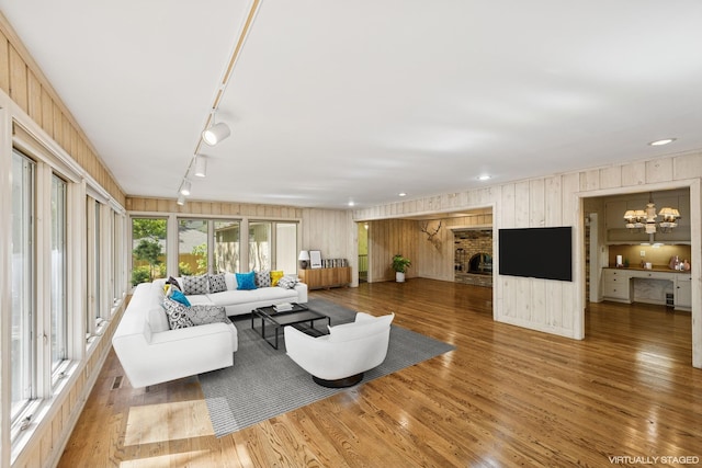 13907 Mcginty Rd E, Minnetonka, MN 55305 - living room with a chandelier, wood finished floors, a fireplace, wooden walls, and rail lighting
