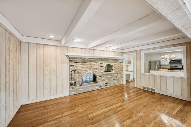 13907 Mcginty Rd E, Minnetonka, MN 55305 - unfurnished living room with wood finished floors, beam ceiling, wooden walls, a chandelier, and a brick fireplace