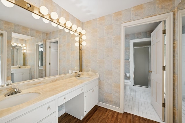13907 Mcginty Rd E, Minnetonka, MN 55305 - bathroom with double vanity, toilet, wood finished floors, tile walls, and a stall shower