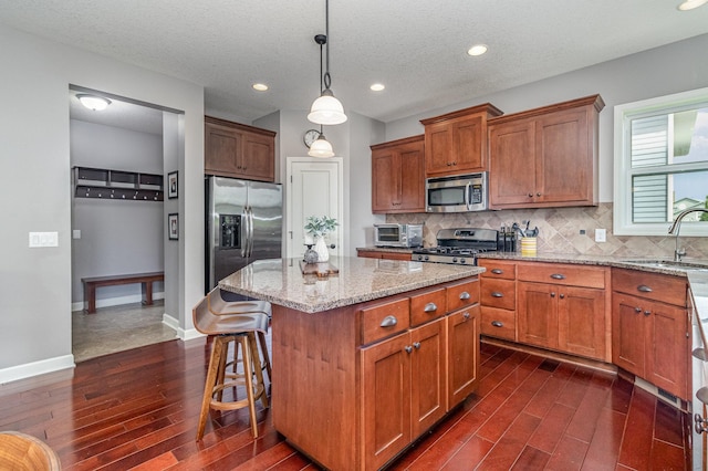 8831 Reflections Rd, Chanhassen, MN 55317 - kitchen with appliances with stainless steel finishes, a sink, dark wood-style flooring, a kitchen island, and light stone counters