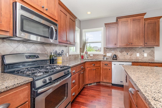 8831 Reflections Rd, Chanhassen, MN 55317 - kitchen with stainless steel appliances, dark wood-style floors, a sink, brown cabinetry, and recessed lighting
