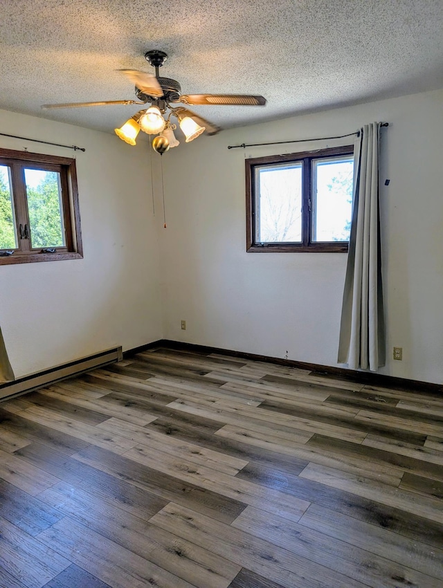spare room featuring wood finished floors, a textured ceiling, ceiling fan, baseboard heating, and baseboards
