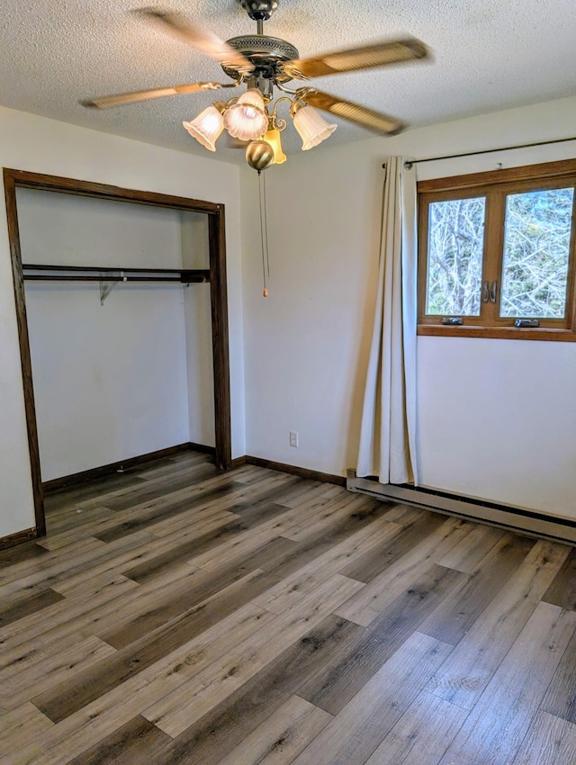 unfurnished bedroom featuring a closet, a textured ceiling, wood finished floors, and baseboards