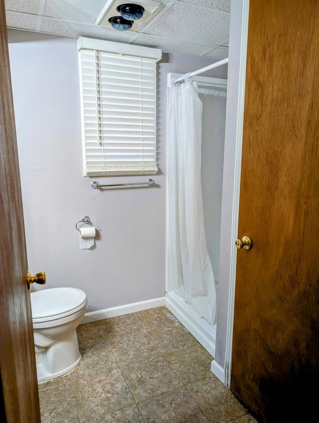 full bathroom featuring toilet, baseboards, a shower stall, and a drop ceiling