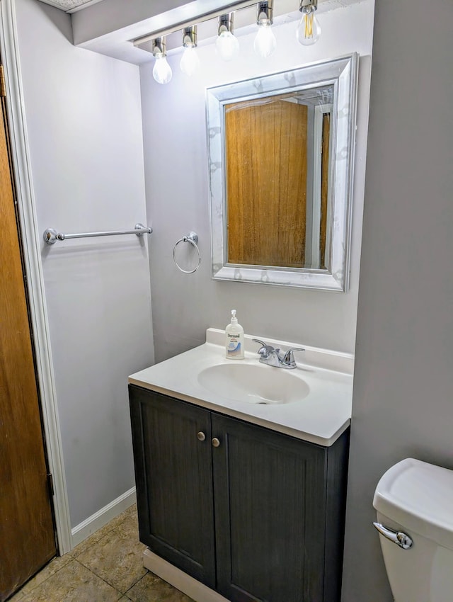 half bathroom featuring vanity, toilet, and baseboards