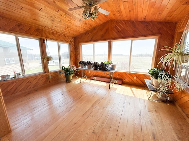 sunroom / solarium with wood walls, hardwood / wood-style flooring, and lofted ceiling