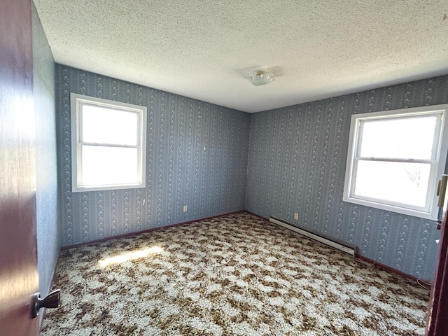 carpeted spare room featuring a baseboard heating unit and a textured ceiling
