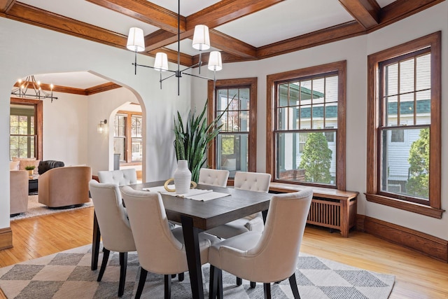 dining space featuring light wood-type flooring, arched walkways, a notable chandelier, and plenty of natural light