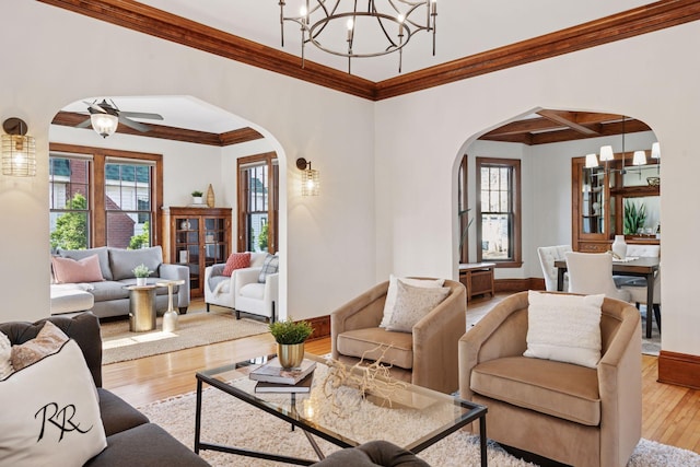living area featuring arched walkways, wood finished floors, and crown molding
