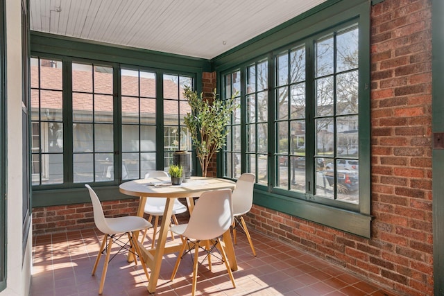sunroom / solarium with french doors, brick wall, and tile patterned flooring