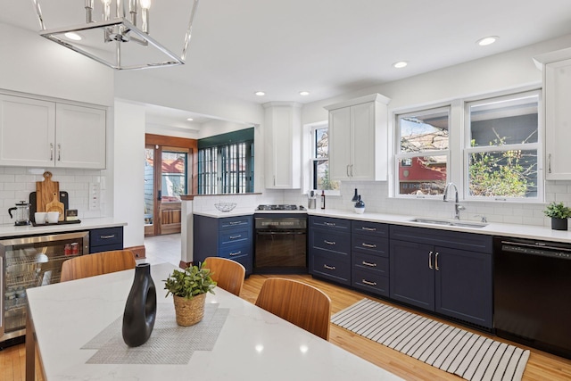 kitchen featuring a sink, black dishwasher, wine cooler, tasteful backsplash, and blue cabinets