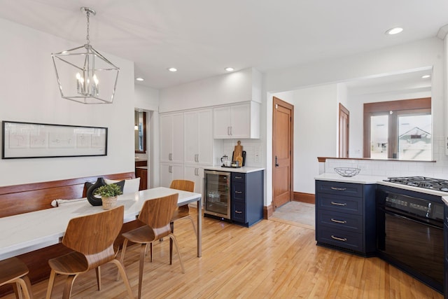 kitchen with decorative backsplash, wine cooler, gas cooktop, black oven, and blue cabinets