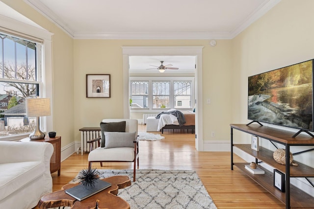 sitting room with baseboards, light wood-type flooring, a ceiling fan, and crown molding