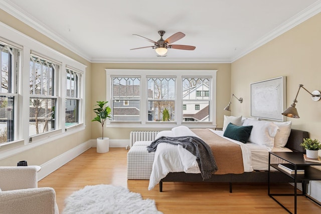 bedroom featuring radiator, crown molding, a ceiling fan, baseboards, and wood finished floors
