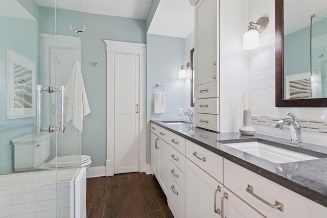 bathroom with double vanity, a sink, wood finished floors, and baseboards