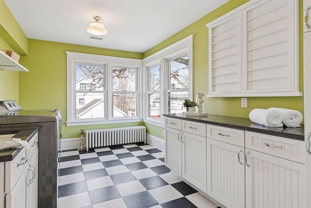 clothes washing area with tile patterned floors, radiator heating unit, independent washer and dryer, and plenty of natural light