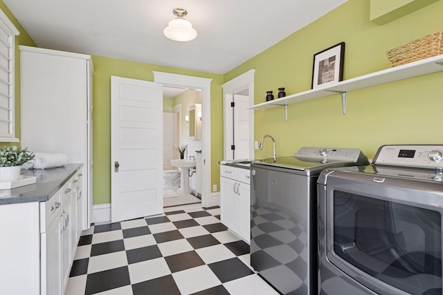 laundry area with dark floors, washer and dryer, cabinet space, and a sink