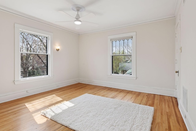 unfurnished room with ornamental molding, baseboards, and light wood-type flooring