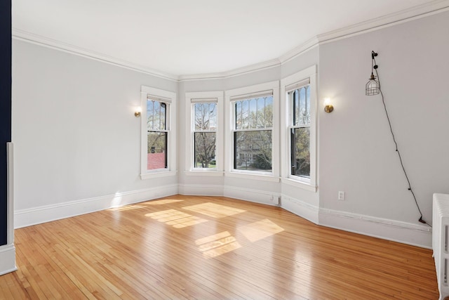 unfurnished room featuring baseboards, crown molding, and wood-type flooring