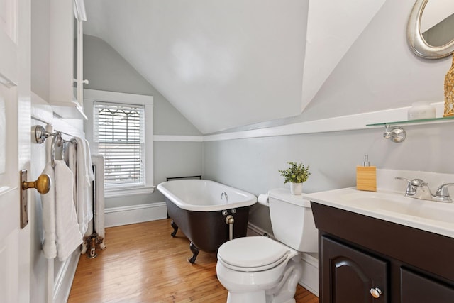 bathroom featuring vanity, toilet, a freestanding bath, vaulted ceiling, and wood finished floors