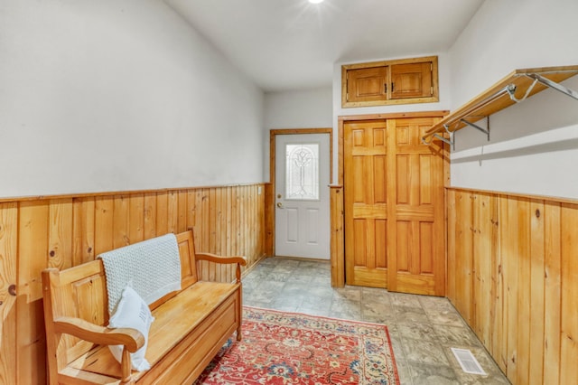entryway with wooden walls, visible vents, and a wainscoted wall