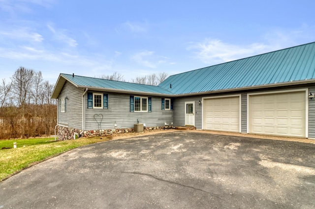 view of front of property featuring an attached garage, driveway, and metal roof