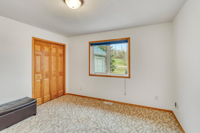 unfurnished bedroom with baseboards, visible vents, carpet, and a closet