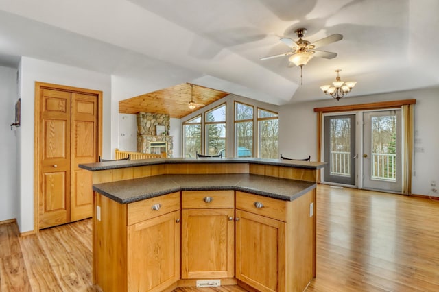 kitchen with dark countertops, a wealth of natural light, ceiling fan with notable chandelier, and light wood-style floors