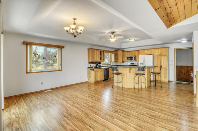 kitchen featuring dark countertops, appliances with stainless steel finishes, a kitchen breakfast bar, and light wood-style flooring