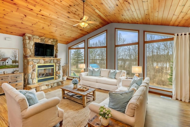 living room with a stone fireplace, wood ceiling, ceiling fan, and vaulted ceiling